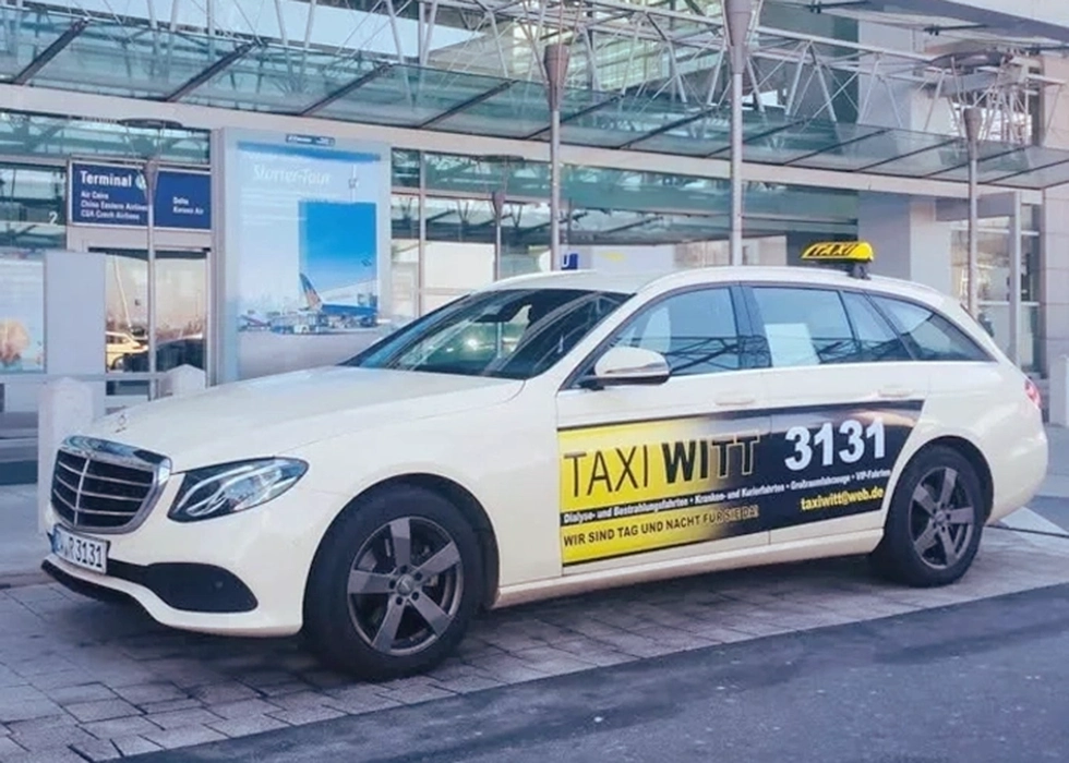 Taxi der Firma Witt parkt auf dem Flughafenparkplatz